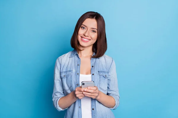 Foto de menina muito positiva sorriso de dente olhar câmera segurar telefone gadget isolado no fundo de cor azul — Fotografia de Stock