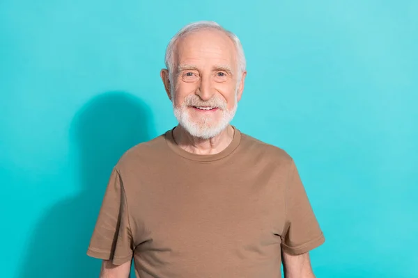 Retrato de conteúdo alegre atraente homem de cabelos grisalhos vestindo tshirt marrom isolado sobre fundo de cor azul vívido — Fotografia de Stock