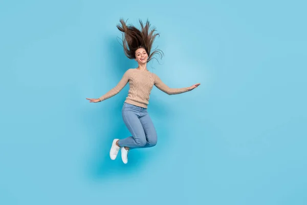 Foto von schönen hübschen fröhlichen Dame springen haben Spaß Windstoß Frisur tragen beige Pullover isoliert blaue Farbe Hintergrund — Stockfoto