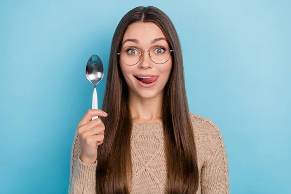 Foto de animado engraçado senhora segurar colher protrude língua lamber lábio desgaste especificações bege suéter isolado azul cor fundo — Fotografia de Stock