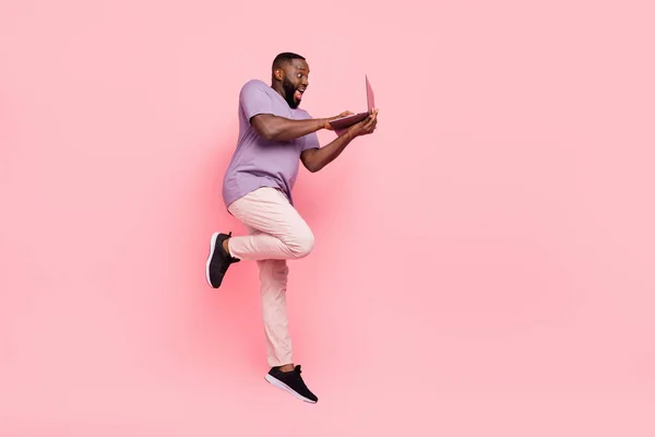 Zdjęcie pod wrażeniem facet nosić fioletowy t-shirt skoki wysokie pisanie nowoczesne urządzenie izolowane różowy kolor tła — Zdjęcie stockowe