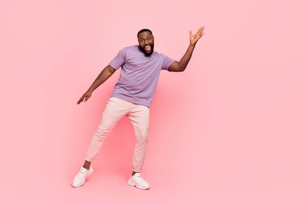 Fotografie vzrušený legrační chlap oblečený fialové tričko s úsměvem tanec izolované růžové barvy pozadí — Stock fotografie