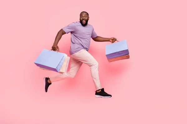 Plná délka velikosti těla pohled na atraktivní veselý chlap skákání přináší dárky izolované přes růžové pastelové barvy pozadí — Stock fotografie