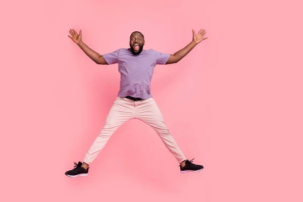 분홍빛 파스텔 색 배경 위로 외딴 곳에서 점프하는 매력적 인 쾌활 한 남자의 전체 몸길이 사진 — 스톡 사진
