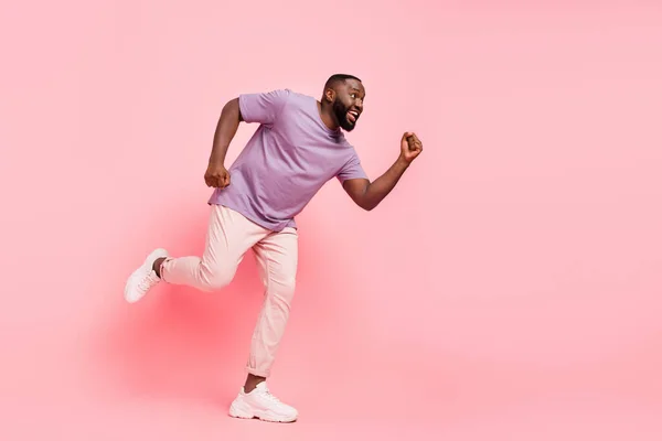 Fotografie atraktivní okouzlující chlap oblečený fialové tričko běží rychle prázdný prostor izolované růžové barvy pozadí — Stock fotografie