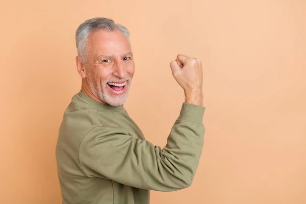 Profile side photo of senior man fists hand sportive celebrate victory awesome isolated over beige color background — Stock Photo, Image