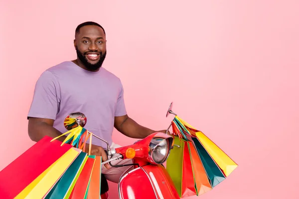 Foto av funky rolig kille bär lila t-shirt ridning moped bär shoppare tomt utrymme isolerad rosa färg bakgrund — Stockfoto