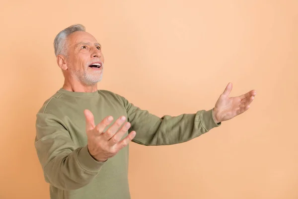 Profiel zijkant foto van opgewonden senior man open armen kijken lege ruimte geïsoleerd over beige kleur achtergrond — Stockfoto