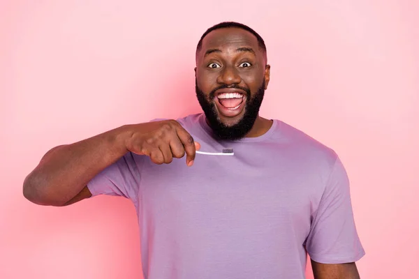 Fotografie ohromen legrační chlap oblečený fialové tričko čištění zubů izolované růžové barvy pozadí — Stock fotografie