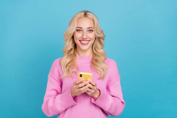 Foto de agradável millennial ondulado loiro senhora segurar telefone desgaste rosa jumper isolado no fundo de cor azul — Fotografia de Stock