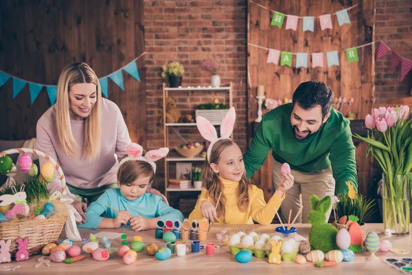 Fotografie krásné mladé rodiny trávit čas doma slavit Velikonoce maminka a tatínek sledovat děti malování vejce, aby dekorace — Stock fotografie