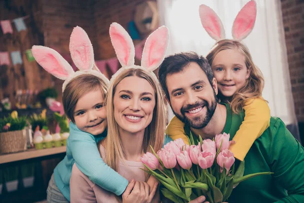 Fotografie roztomilé krásné rodiny s králičí uši oslavit velikonoční dovolenou otec držet dárek pro matku kytici květin — Stock fotografie