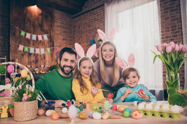 Fotografie pozitivních veselých čtyř lidí těšit malovat vejce připravit velikonoční koš dům uvnitř — Stock fotografie
