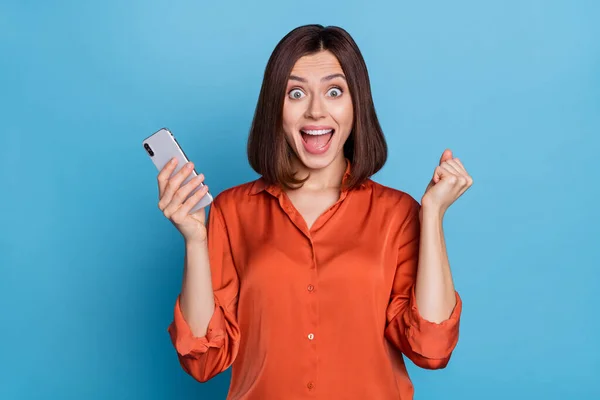 Foto de joven dama celebrar éxito puños manos venta celebrar teléfono celular lotería extática aislado sobre fondo de color azul —  Fotos de Stock