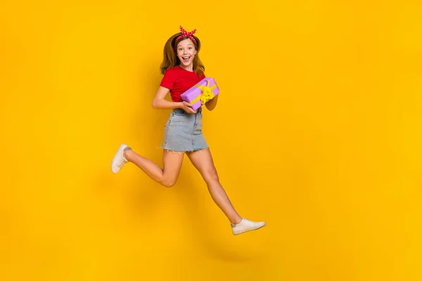 Ganzkörperfoto von coolen kleinen Mädchen laufen Geburtstag tragen T-Shirt Haarband Rock Turnschuhe isoliert auf gelbem Hintergrund — Stockfoto
