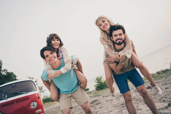 Foto de jovens casais stand piggyback perto do mar minian viagem de férias usar pano hippie ao ar livre fora — Fotografia de Stock