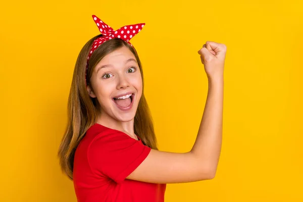 Foto del lado del perfil de linda niña adorable levantar los puños en el logro de la victoria mujer poder aislado en el fondo de color amarillo — Foto de Stock