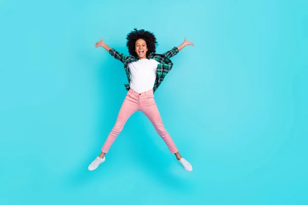 Photo of cheerful crazy active lady jump raise hands have fun wear checkered shirt isolated teal color background — Stock Photo, Image