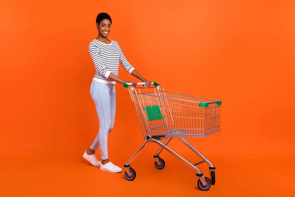 Parlak turuncu arka planda izole edilmiş, çekici, neşeli bir kızın mağaza alışverişinin boy boy boy görünümü — Stok fotoğraf