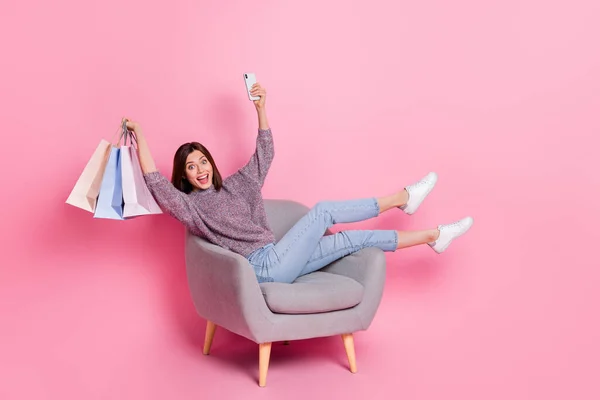 Foto de encantadora mulher excitada usar pulôver sentado cadeira levantando pechinchas moderno dispositivo isolado cor-de-rosa fundo — Fotografia de Stock