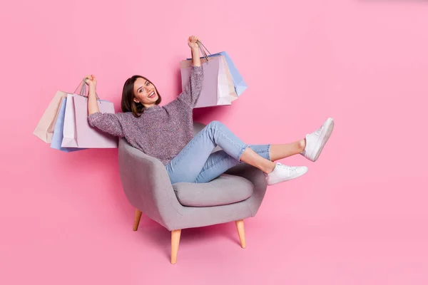 Retrato de menina alegre atraente sentado em sacos de segurando poltrona se divertindo isolado sobre fundo cor pastel rosa — Fotografia de Stock