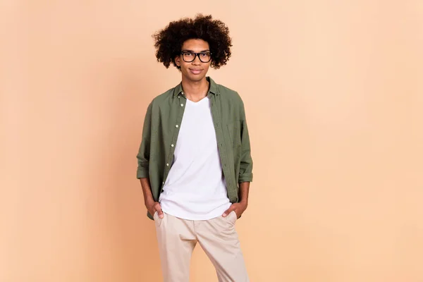 Portret van aantrekkelijke inhoud geschoolde intellectuele man geek hand in hand in zakken geïsoleerd over beige pastel kleur achtergrond — Stockfoto