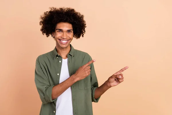 Portrait of attractive cheerful wavy-haired guy demonstrating copy space ad advert isolated over beige pastel color background — Stock Photo, Image