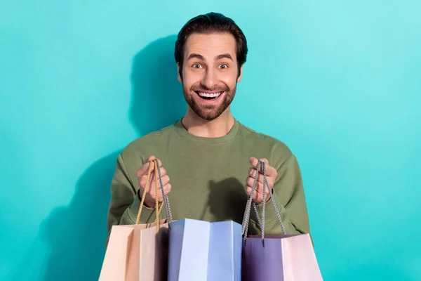Фото молодого веселого чоловіка отримати подарунок тримайте сумки річниці ізольовані на бірюзовому кольоровому фоні — стокове фото