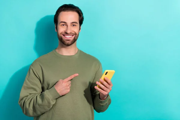 ファンキーなブルネット千年男インデックスの写真電話は、電話の色の背景に隔離されたカーキのスウェットシャツを身に着けている — ストック写真