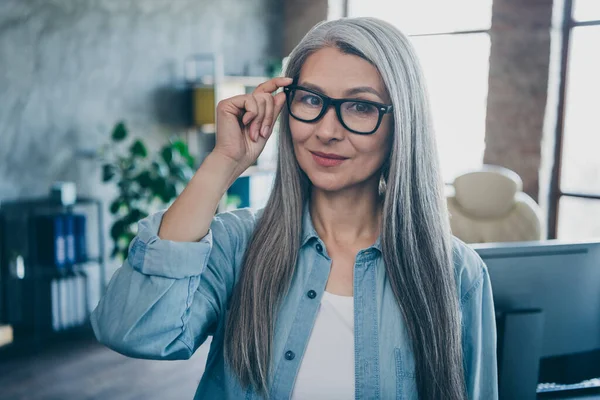 Ritratto di affascinante soddisfatto invecchiato signora mano tocco occhiali sguardo fotocamera luce diurna workstation indoor — Foto Stock