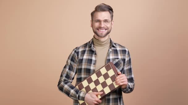 Inteligente chico mantenga tablero de ajedrez listo concurso aislado pastel color fondo — Vídeos de Stock
