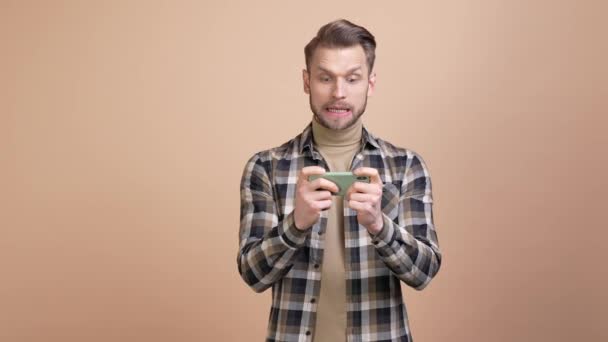 Возбужденный парень играть гаджет игры кулак вверх выиграть изолированный пастельный цвет фона — стоковое видео