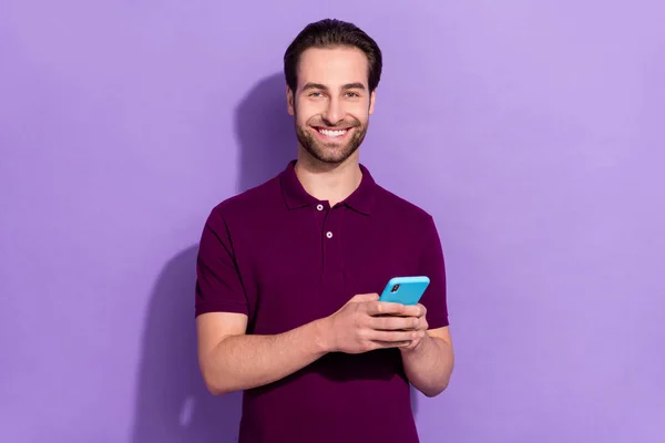 Foto van jonge vrolijke influencer jongen chatten met vrienden in de telefoon geïsoleerd op paarse kleur achtergrond — Stockfoto