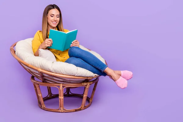 Foto de comprimento total de jovem menina alegre em aconchegante poltrona confortável leitura livro favorito isolado no fundo de cor roxa — Fotografia de Stock