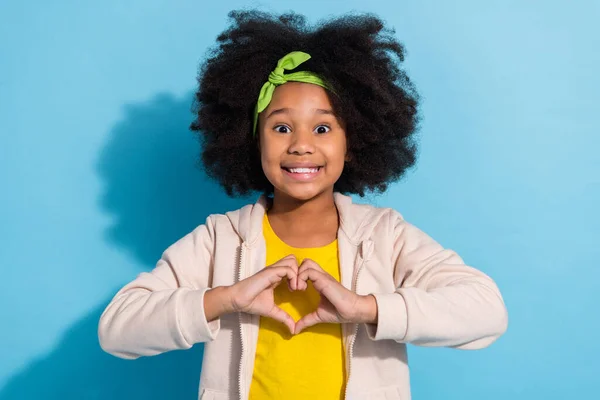 Retrato de moda atractiva divertida niña alegre colegiala mostrando la forma del corazón aislado sobre fondo de color azul brillante —  Fotos de Stock