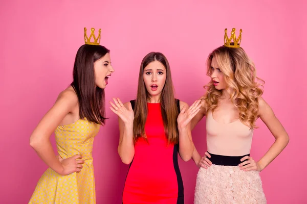 Foto de tres chicas atractivas usan corona gritan furiosos entre sí aislados en el fondo de color rosa —  Fotos de Stock