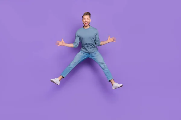Bild av glada imponerad kille bära grå skjorta hoppa högt som stjärna isolerad violett färg bakgrund — Stockfoto