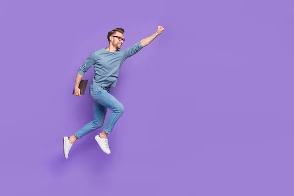 Фото счастливчика в очках в серой рубашке прыгающего высоко держащего устройства пустое пространство изолированного фиолетового цвета фона — стоковое фото