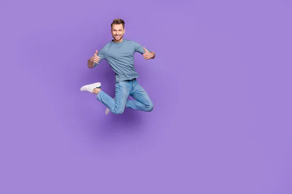 Фото досить впевненого хлопця в сірій сорочці, що стрибає з високими пальцями вгору порожній простір ізольований фіолетовий кольоровий фон — стокове фото