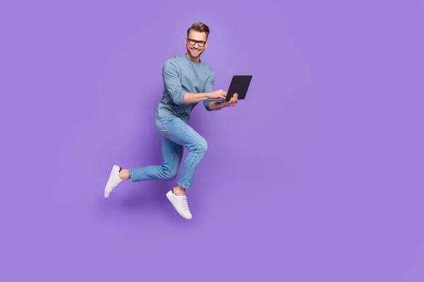 Foto de bastante guapo chico vestido gris camisa gafas saltando alto chat moderno gadget aislado color púrpura fondo —  Fotos de Stock