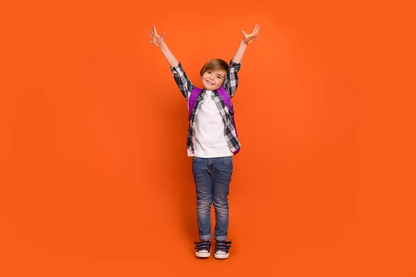 Pełna długość zdjęcie młodego wesołego chłopca dobry nastrój trzymać ramiona w górę izolowane na pomarańczowym tle kolor — Zdjęcie stockowe