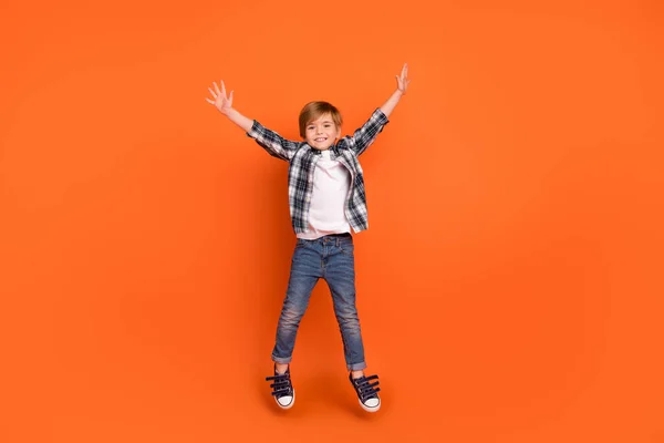 Full length foto di giovane ragazzo allegro divertirsi saltare fino usura vestito moderno isolato su sfondo di colore arancione — Foto Stock