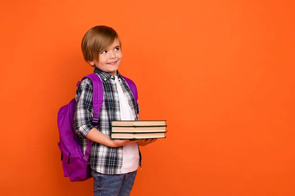 Profil boční fotografie mladého chlapce zvědavý myslet chytrý vzhled prázdný prostor držet knihu encyklopedie izolované přes oranžové barvy pozadí — Stock fotografie