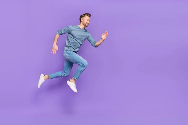 Foto van knappe charmante man gekleed grijs shirt springen hoog lopende snelle lege ruimte geïsoleerde paarse kleur achtergrond — Stockfoto