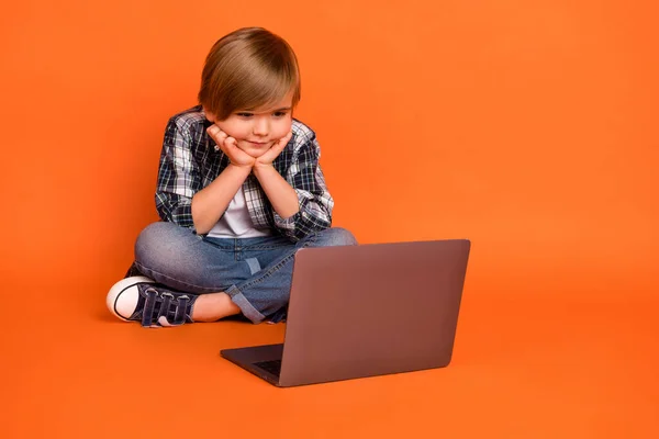 Pełna długość zdjęcie młodego chłopca ręce dotyk policzki oglądać film laptop weekend izolowany ponad pomarańczowy kolor tła — Zdjęcie stockowe