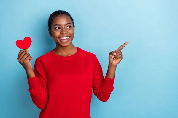 Foto de la señora morena milenaria impresionada sostiene índice de corazón espacio vacío desgaste jersey rojo aislado sobre fondo de color azul —  Fotos de Stock