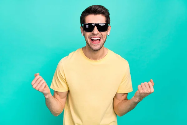 Foto de brunet millennial chico escuchar música desgaste gafas camiseta auriculares aislados sobre fondo de color verde azulado —  Fotos de Stock