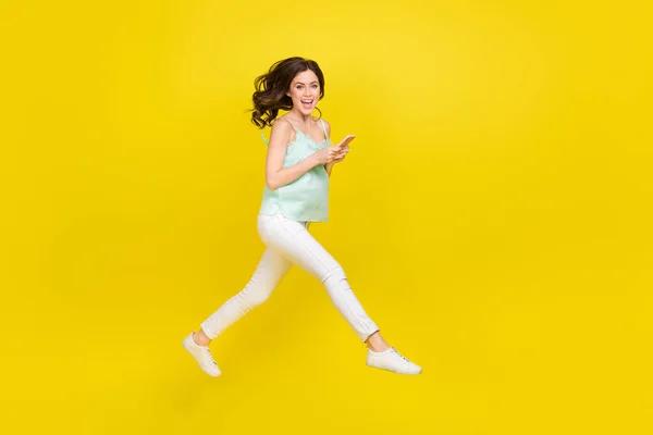 Foto lateral de perfil em tamanho completo de uma jovem encantada e alegre aproveite o smartphone de surfe de verão isolado no fundo de cor amarela — Fotografia de Stock