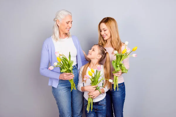 Ritratto di tre persone piuttosto affascinanti tenere mazzo fiori freschi isolati su sfondo di colore grigio — Foto Stock