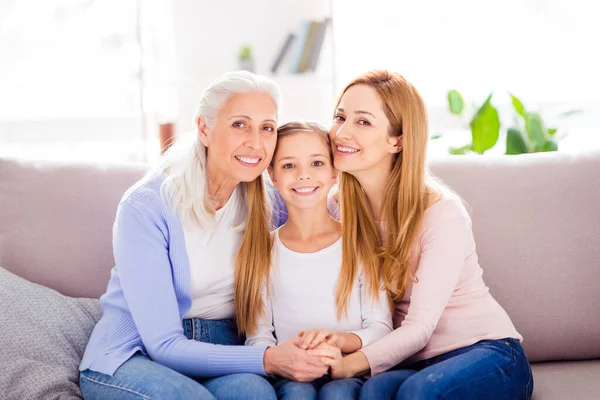 Porträt von drei friedlichen, zufriedenen Menschen, die auf dem Sofa sitzen und Arm in Arm den Wochenendtag genießen — Stockfoto